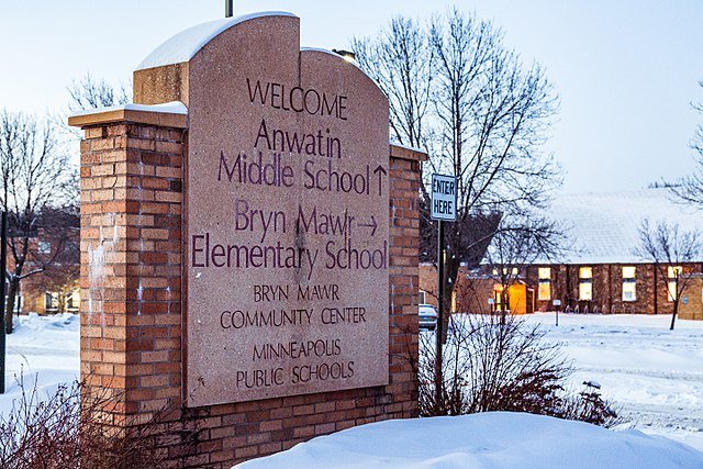 Sign at Anwaatin Middle School and Bryn Mawr Elementary School in Minneapolis, featuring community center information and surrounded by snow-covered landscape.