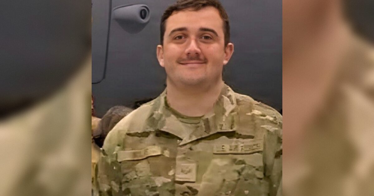 Smiling military personnel in camouflage uniform poses for a photo, showcasing camaraderie and service in a military setting.