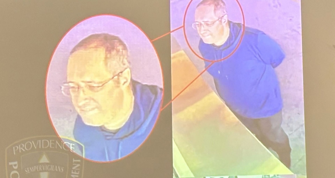 Surveillance image showing a man in a blue hoodie, captured by Providence Police Department, highlighting his face and profile for identification purposes.