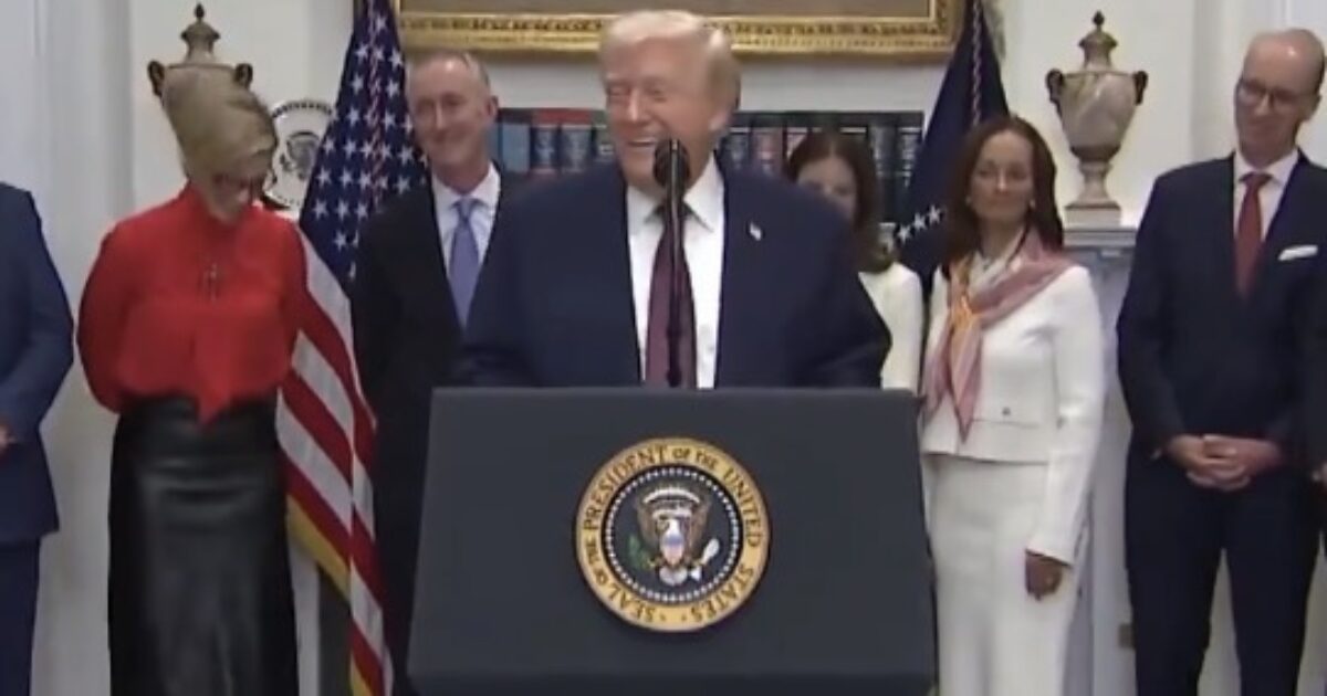 Former President Donald Trump speaking at a podium in the White House, surrounded by officials and flags, during a press event.