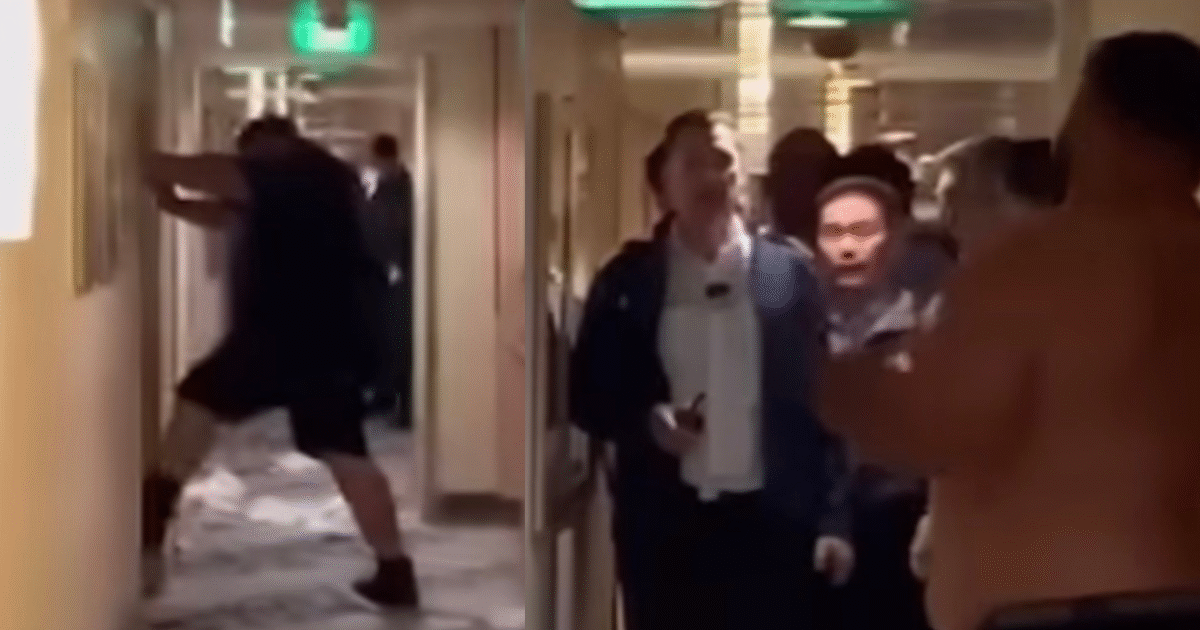 A chaotic scene in a hotel hallway with a shirtless man confronting others while a crowd watches in surprise.