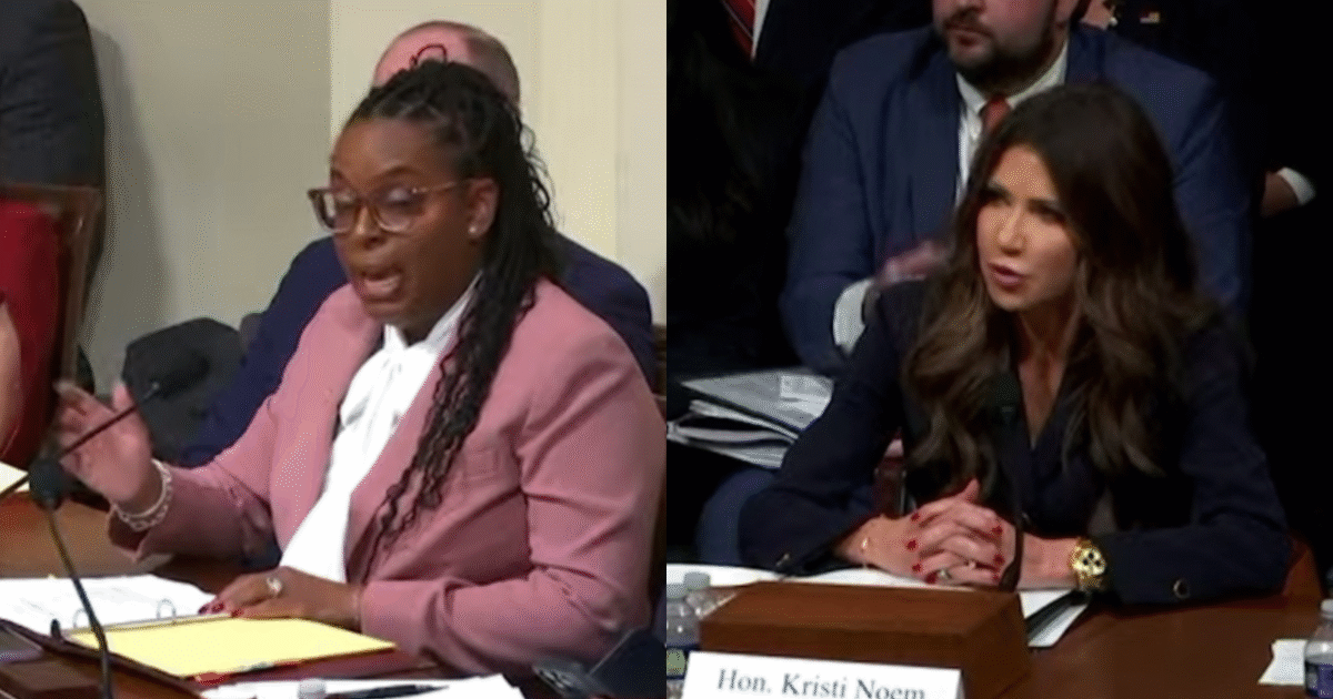 Two women engaged in a discussion during a legislative hearing, one speaking passionately while the other listens intently, with an audience in the background.