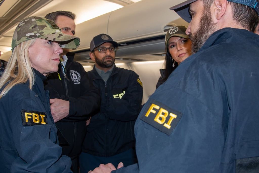 FBI agents in tactical gear engage in discussion on an airplane, showcasing a serious law enforcement situation.