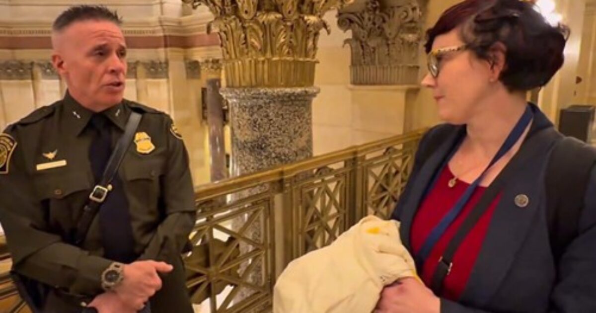 Law enforcement officer speaking with a woman in a historic building, discussing important matters in a formal setting.
