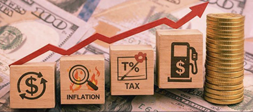 Wooden blocks illustrating economic concepts like inflation, tax, and rising costs, with a background of money and stacked coins, representing financial growth and challenges.