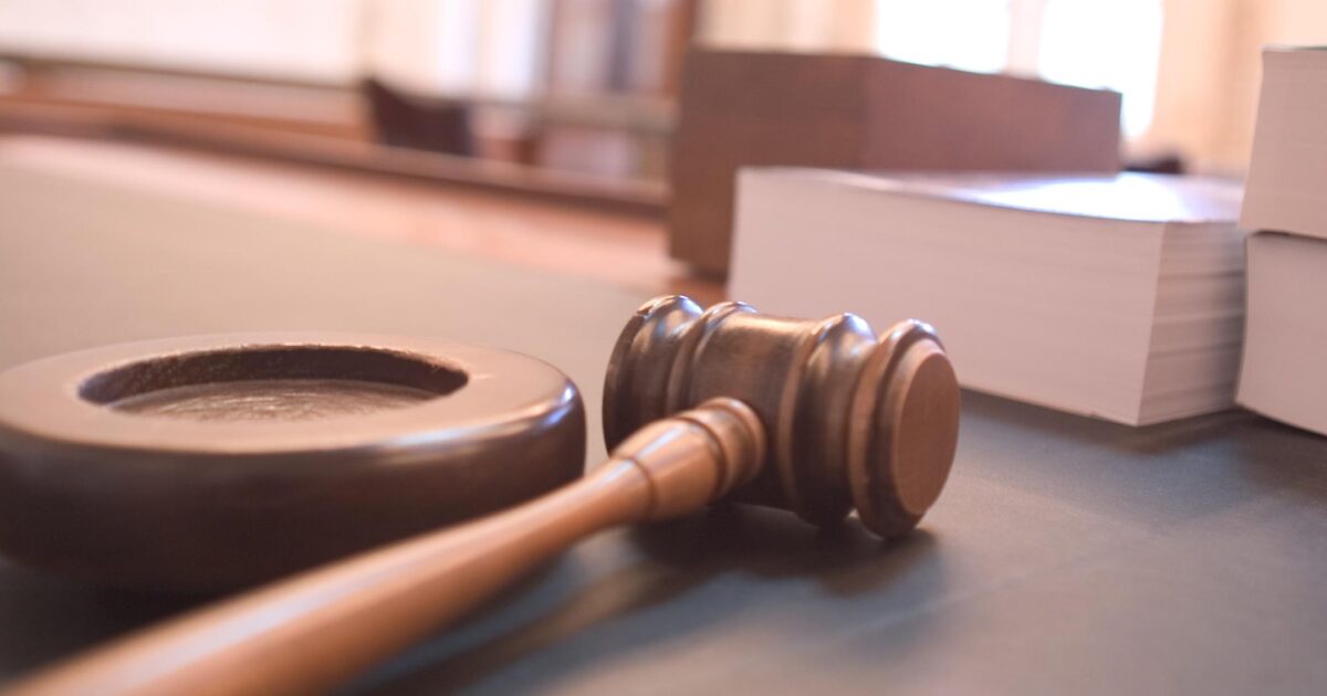 Close-up of a wooden gavel and sound block on a courtroom table, symbolizing justice and legal proceedings.