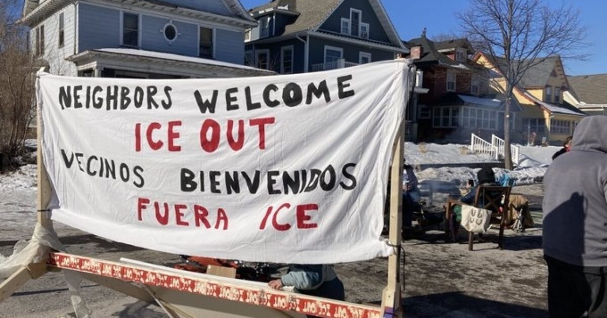 Banner reading "Neighbors Welcome ICE Out" displayed at a community gathering, promoting solidarity and support against ICE in a snowy neighborhood setting.