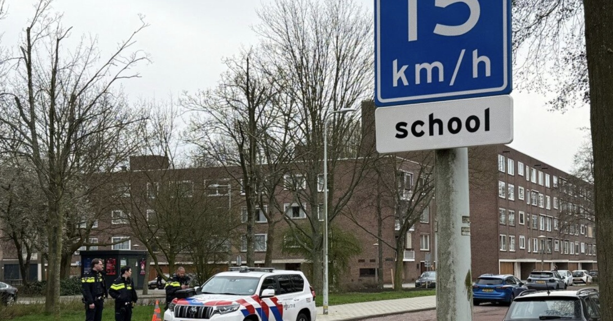 Police officers monitor traffic near a school, with a sign indicating a 15 km/h speed limit for safety.