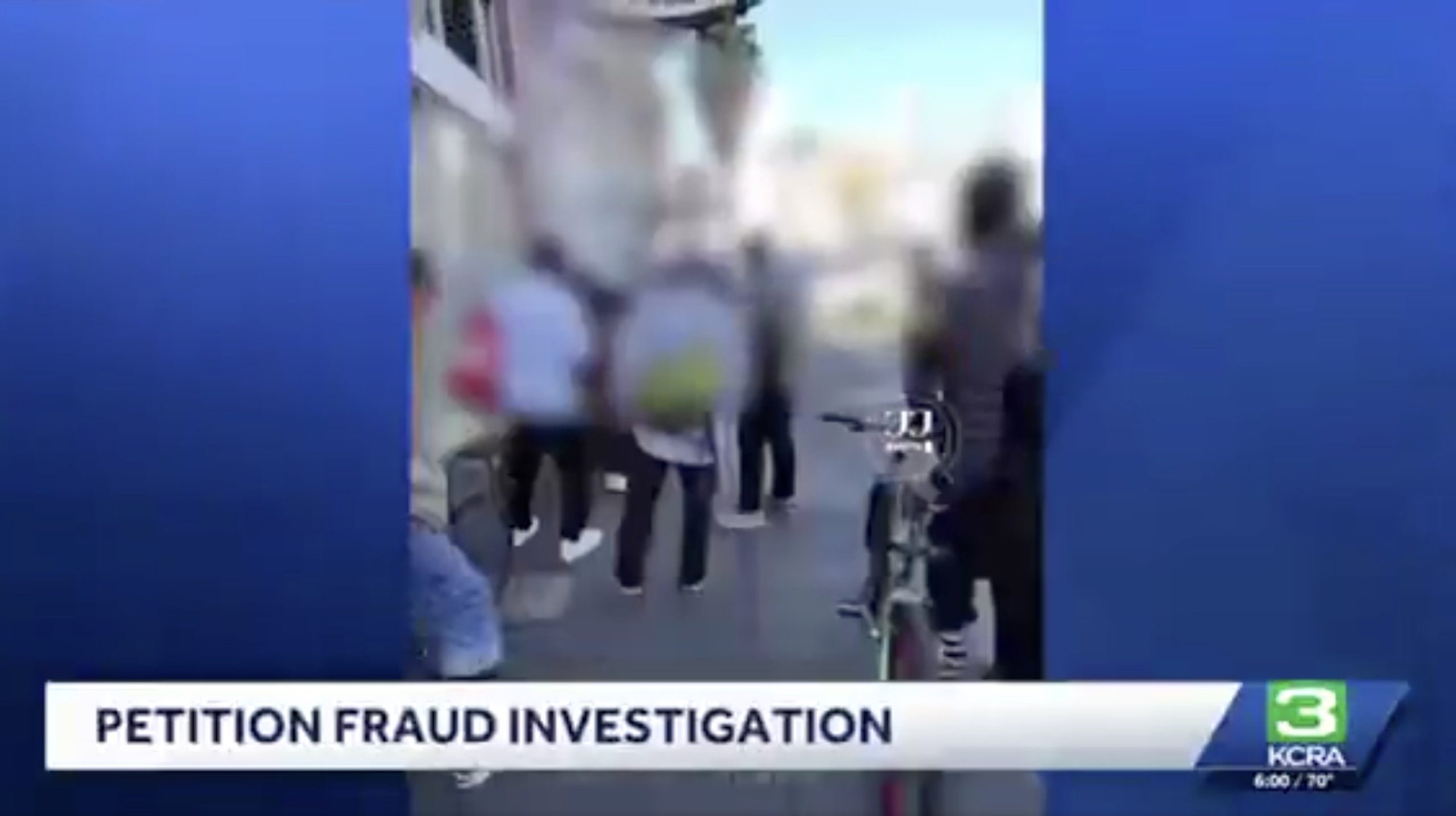 Crowd gathered outside for a petition fraud investigation, with individuals visible discussing the matter and a bicycle parked nearby.