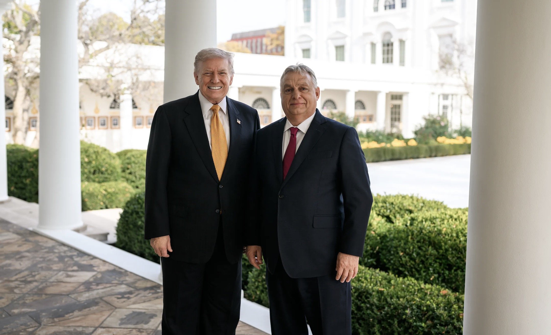 Former US President Donald Trump and Hungarian Prime Minister Viktor Orbán pose together outside the White House, showcasing a diplomatic meeting amid lush greenery.