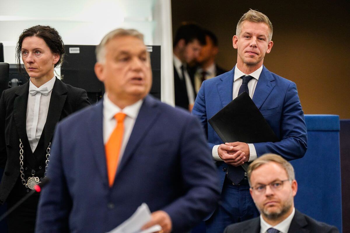 Hungarian political figures engage in a discussion during a parliamentary session, showcasing formal attire and an attentive atmosphere in a legislative setting.