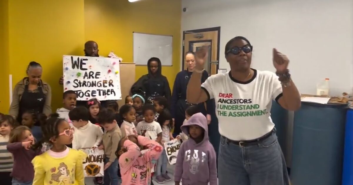 A diverse group of children and adults participate in a community event, holding signs and engaging in a lively discussion about unity and empowerment.