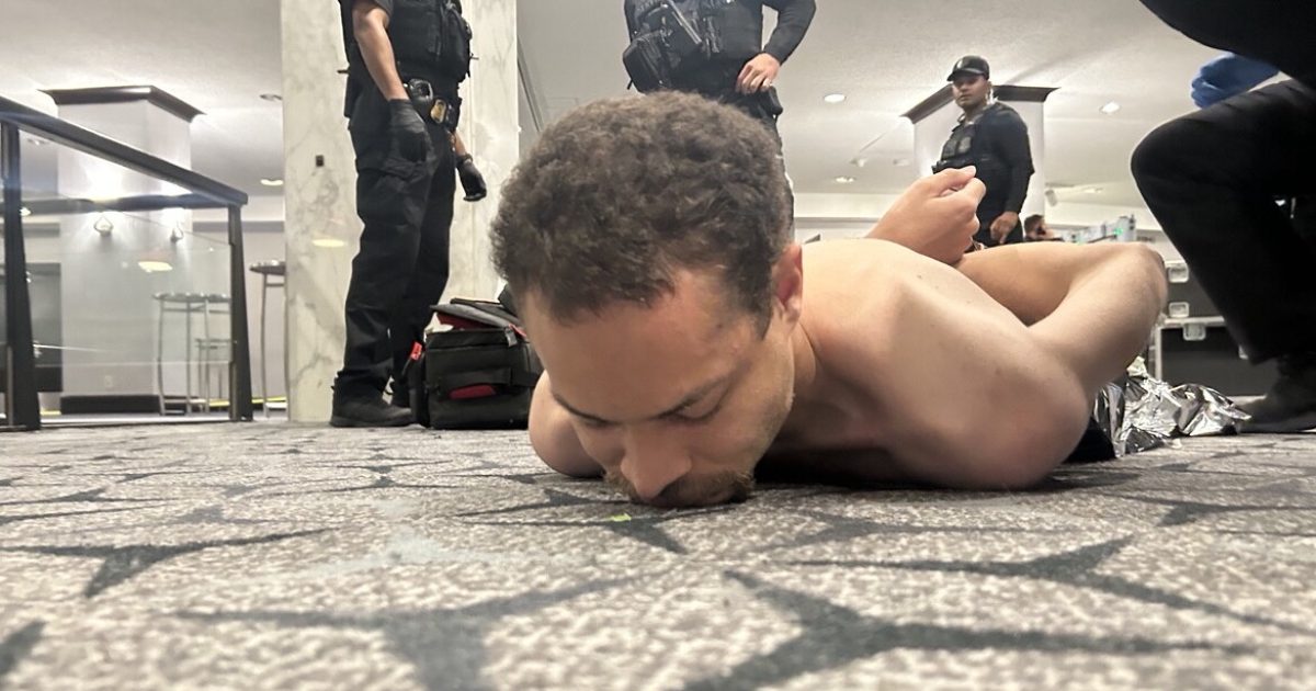 Police officers respond to a situation involving a man lying on the floor in a public space, highlighting a tense moment during an intervention.