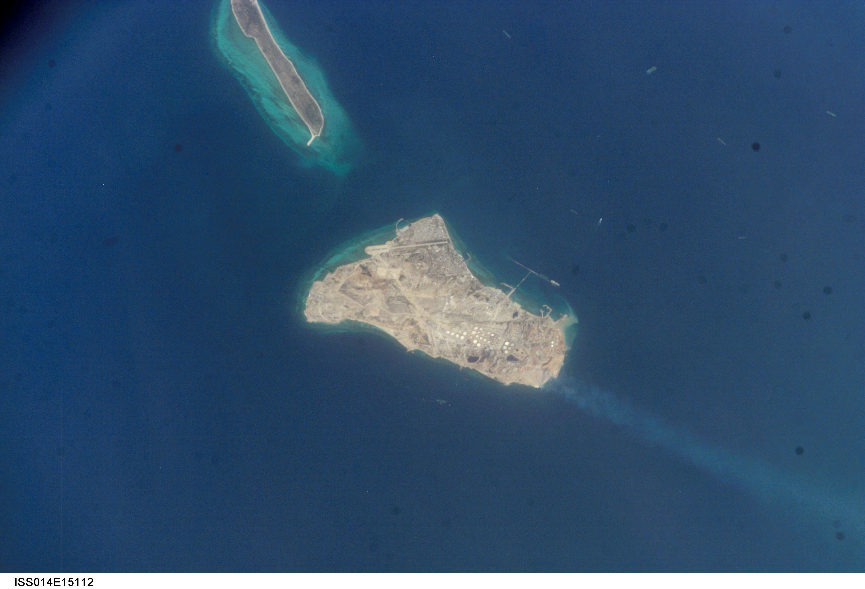 Aerial view of a small island surrounded by deep blue ocean, showcasing land features and nearby coastal formations.