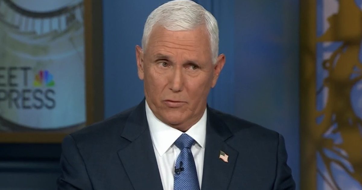 Mike Pence speaking during an interview on Meet the Press, wearing a suit and tie with an American flag pin.