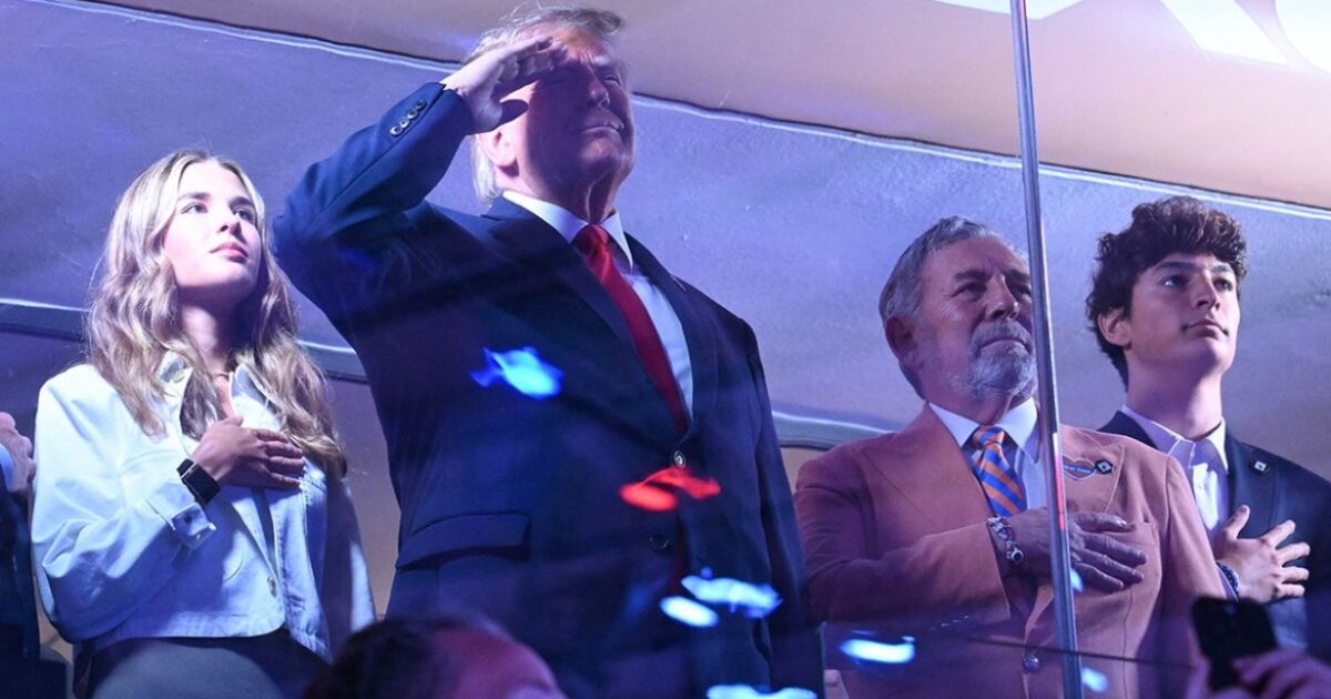 Donald Trump and others standing with hands over their hearts, saluting during an event, showcasing a moment of patriotism and respect.