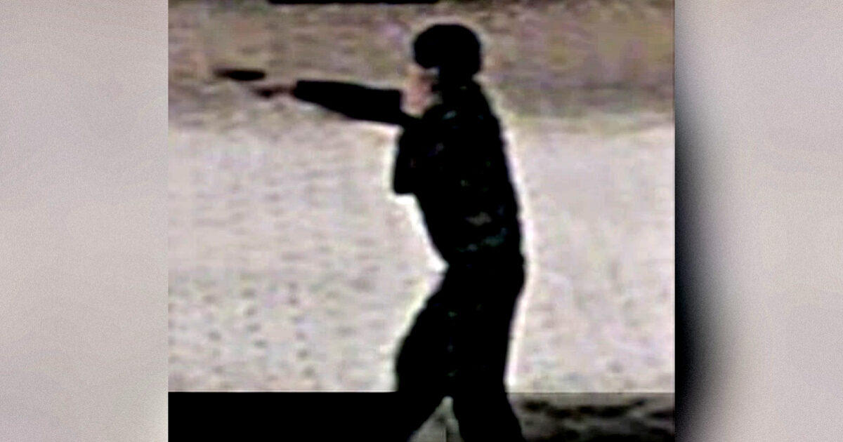 Silhouette of a person in dark clothing aiming a firearm against a blurred background, highlighting a tense moment.