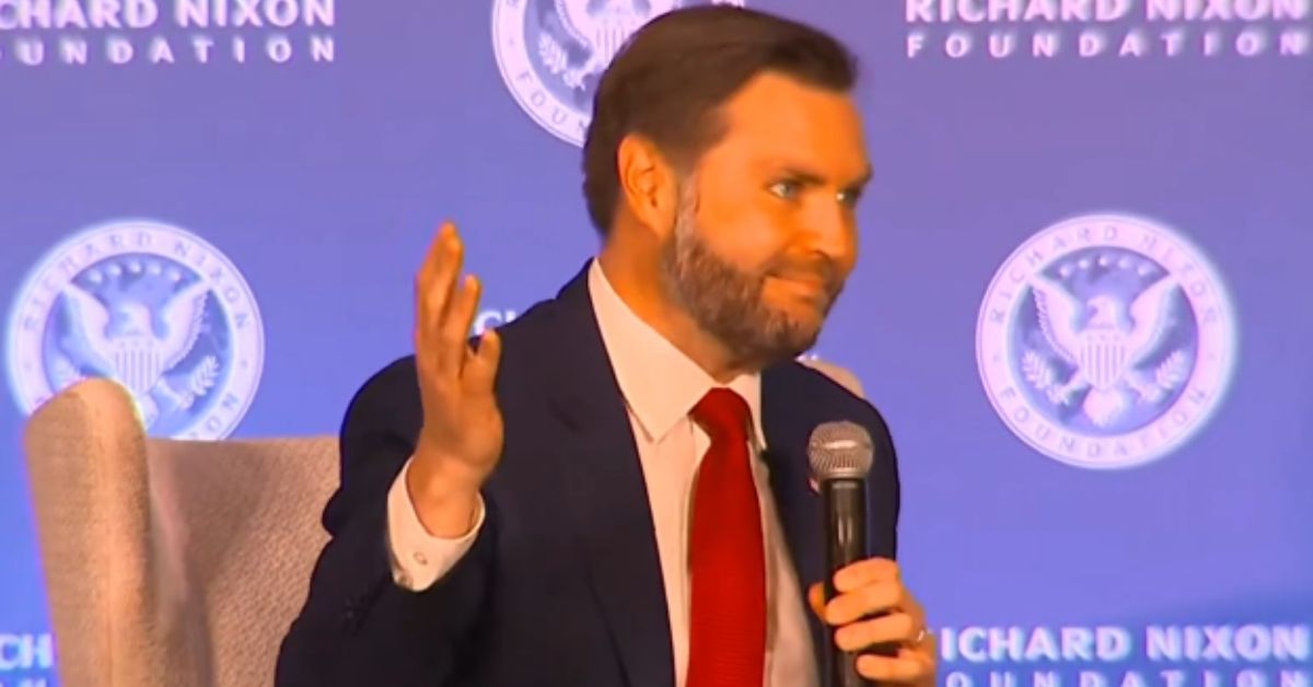 Speaker discussing topics at the Richard Nixon Foundation event, holding a microphone with a blue background and foundation logo.