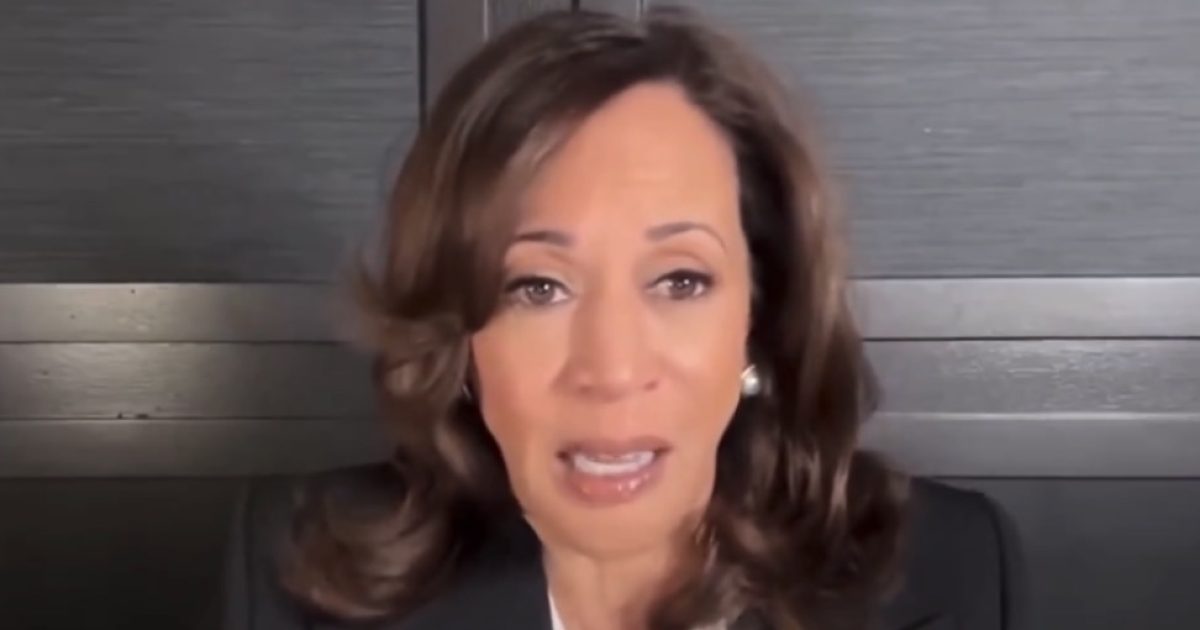 Close-up of a woman with medium-length brown hair speaking passionately in front of a dark background, conveying a serious message.