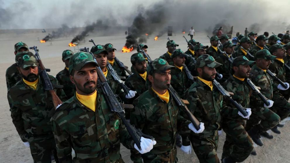 Soldiers in camouflage uniforms and yellow neckerchiefs participate in a military parade, showcasing discipline and readiness in a smoky, outdoor setting.