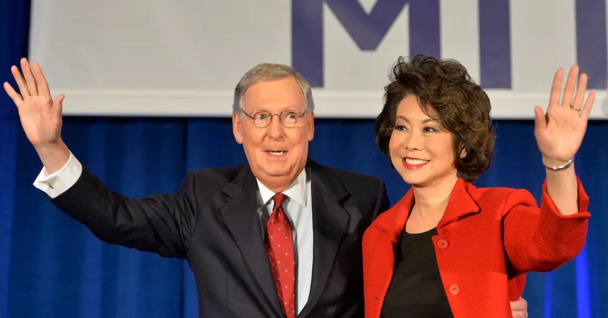 Mitch McConnell and Elaine Chao wave to the audience at a political event, showcasing their camaraderie and leadership.