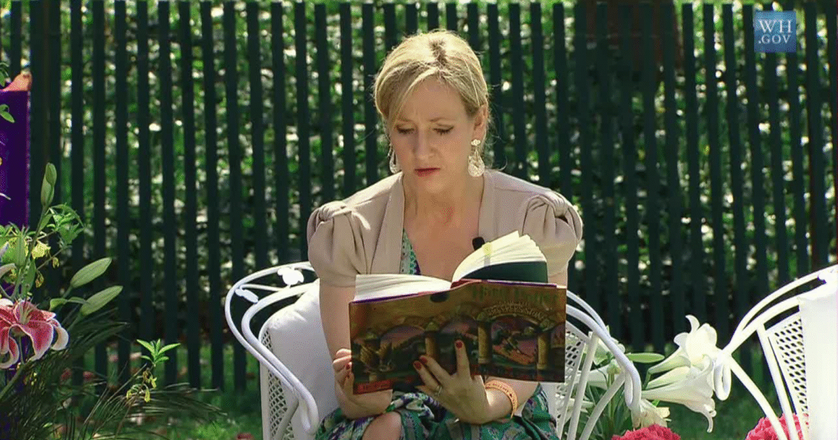 Author JK Rowling, reading a book in a garden setting, surrounded by flowers and greenery, capturing a moment of literary engagement.