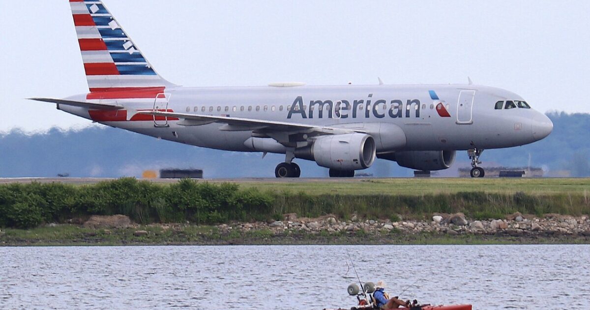 American Airlines plane taxiing near a kayak with two fishermen on a calm waterway.