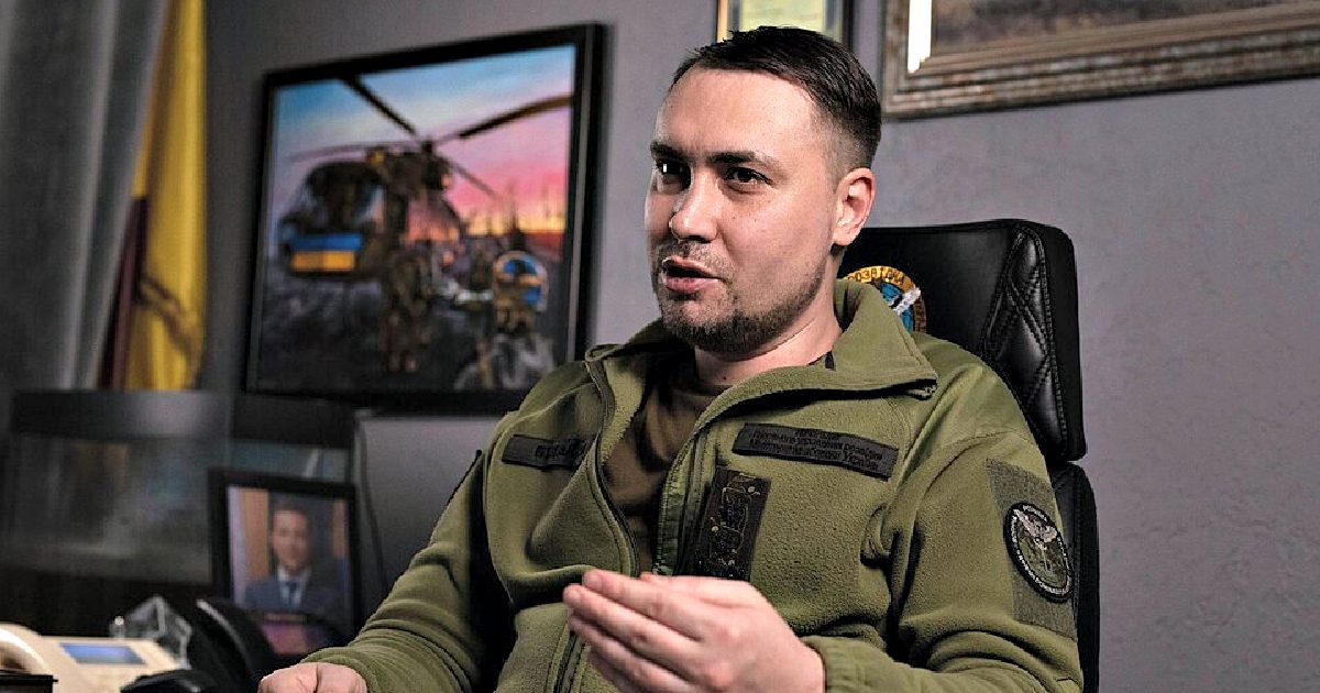 Military official discussing strategy in an office, featuring a helicopter painting and framed photographs in the background.