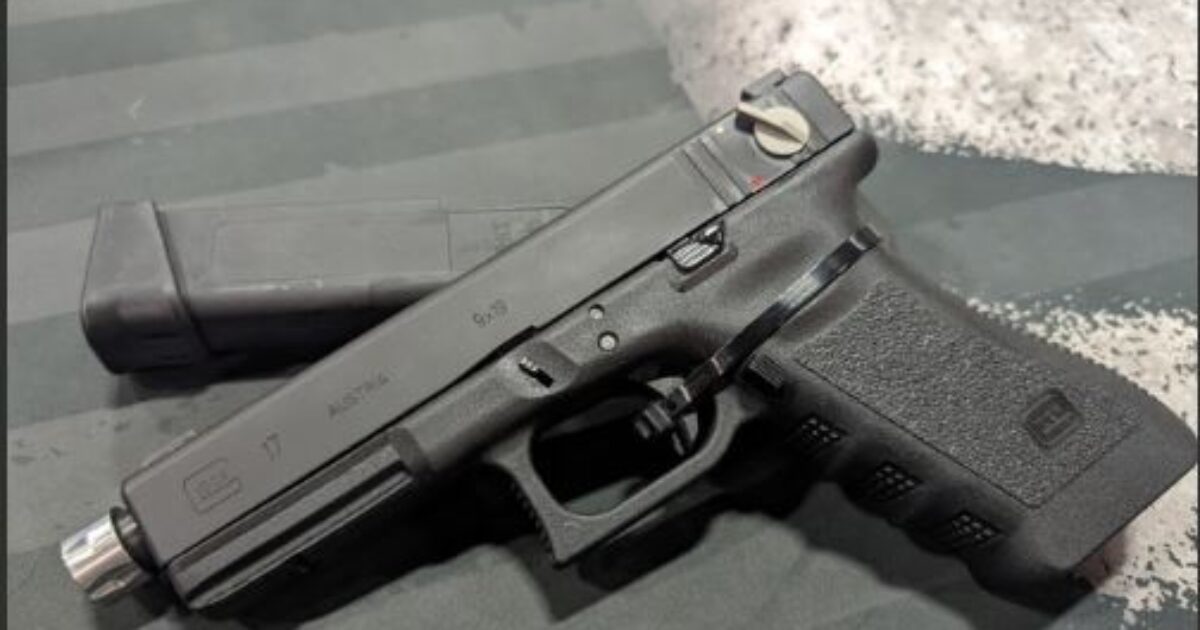 Glock 17 handgun displayed on a textured surface with a magazine beside it, showcasing its design and features.